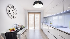 Una cocina moderna con armarios blancos, una lámpara colgante negra y un reloj de pared.