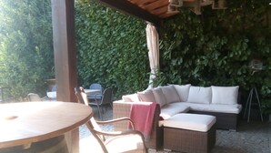 An outdoor patio with a round wooden table, wicker furniture, and a white cushioned sofa. - My Portugal for all Lousada Villa (LOUSADA)