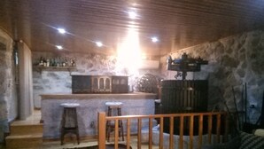 A rustic interior with a bar area, wooden steps, and a stone wall. - My Portugal for all Lousada Villa (LOUSADA)