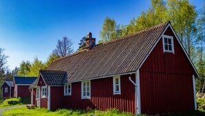 A red wooden building with a sloped roof, a chimney, and a window. - A 19th century village where you live in the middle of the forest among Deer and Elk. (Perstorp)