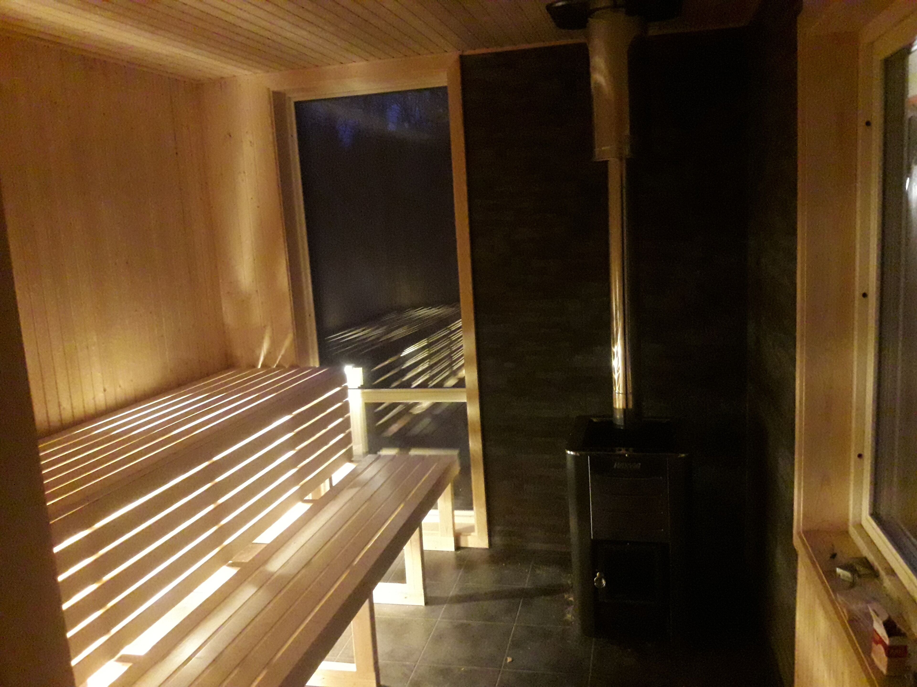 Un sauna avec des bancs en bois et un appareil de chauffage noir.