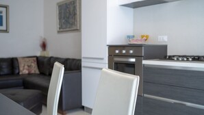 A modern kitchen with a dining area, a sofa, and a painting on the wall.