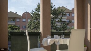 A balcony with a table set for two, chairs, and a view of residential buildings.
