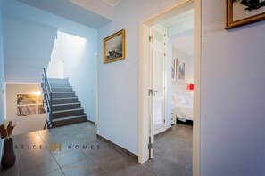 Staircase leads to an upper level with a bedroom featuring a bed and nightstand.