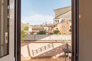 Une vue depuis un balcon, avec un mur en béton, une rambarde en métal et, au loin, un bâtiment surmonté d’un dôme.