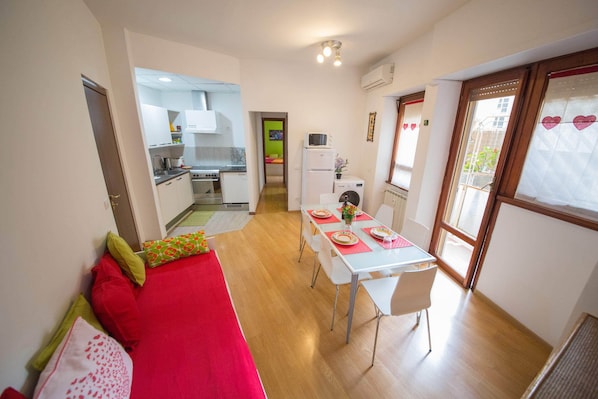 A compact living space with a kitchenette, a dining area, and a sofa.