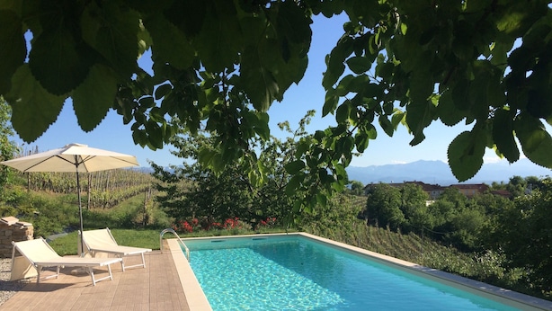 Une piscine rectangulaire à l’eau d’un bleu cristallin, entourée d’une terrasse en bois et agrémentée de deux chaises longues beiges.