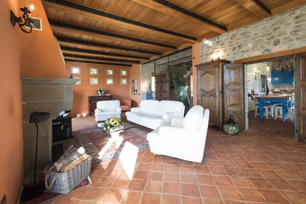 Amplia sala de estar con chimenea, sofás blancos y una pared de piedra.