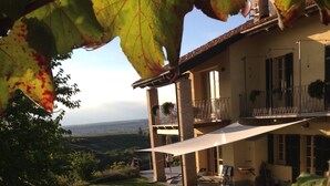 Une maison à deux étages avec un balcon, une pelouse et une vue sur la campagne.