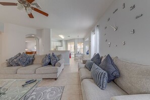 A spacious living room with two sofas, a coffee table, and a wall clock.