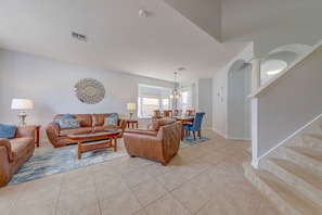 A spacious living room with a brown leather sofa set, a coffee table, and a dining area with a table and chairs.