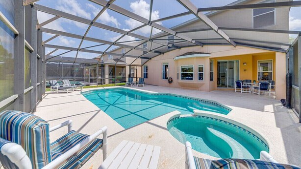 Une piscine extérieure couverte, dotée de chaises longues et d’un espace patio.