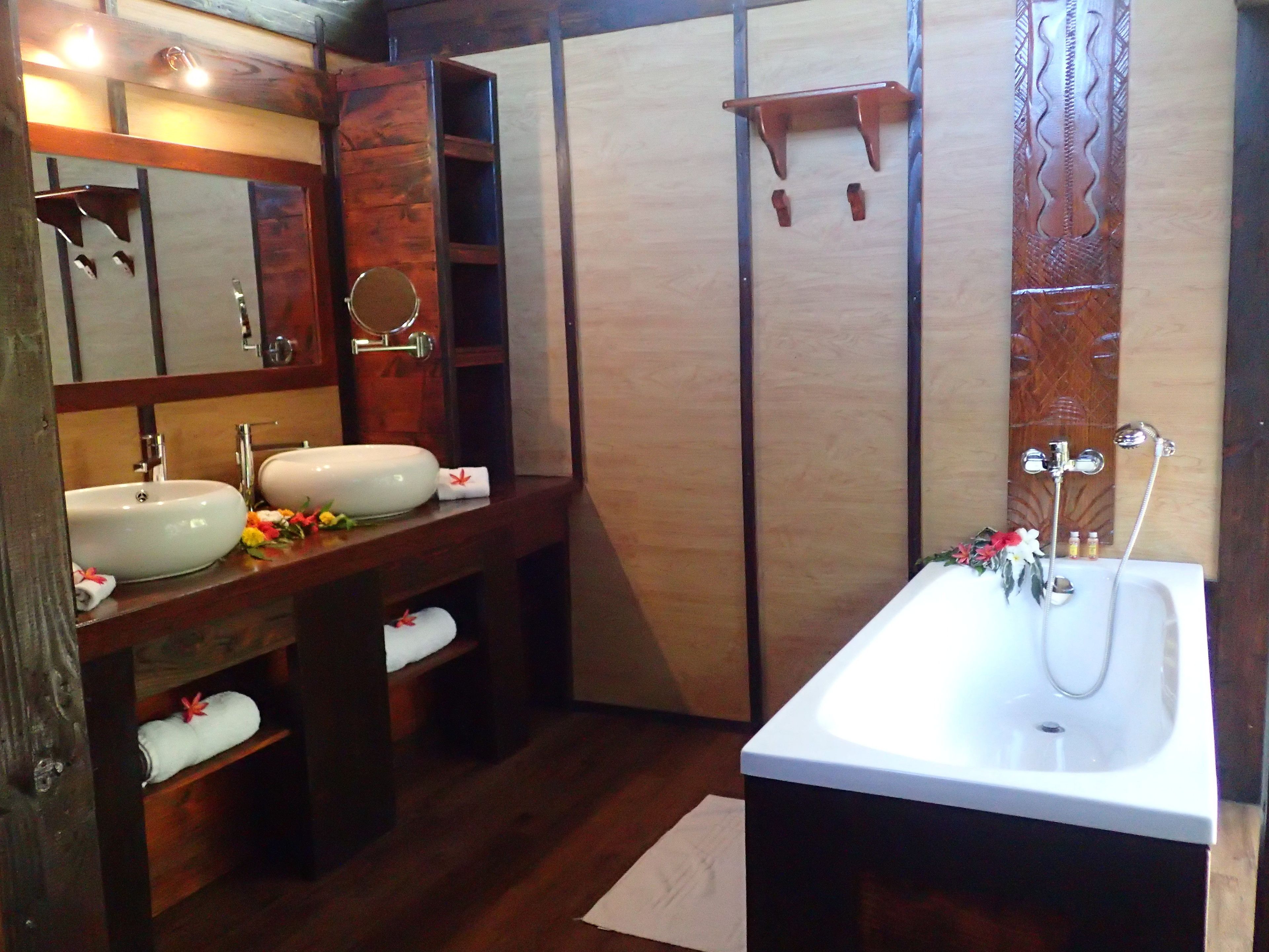 Ein Badezimmer mit zwei Waschbecken, einem Spiegel, einer Dusche und Holzvertäfelung.