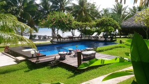 Un espace piscine avec des chaises longues, une terrasse en bois et une vue sur la mer.