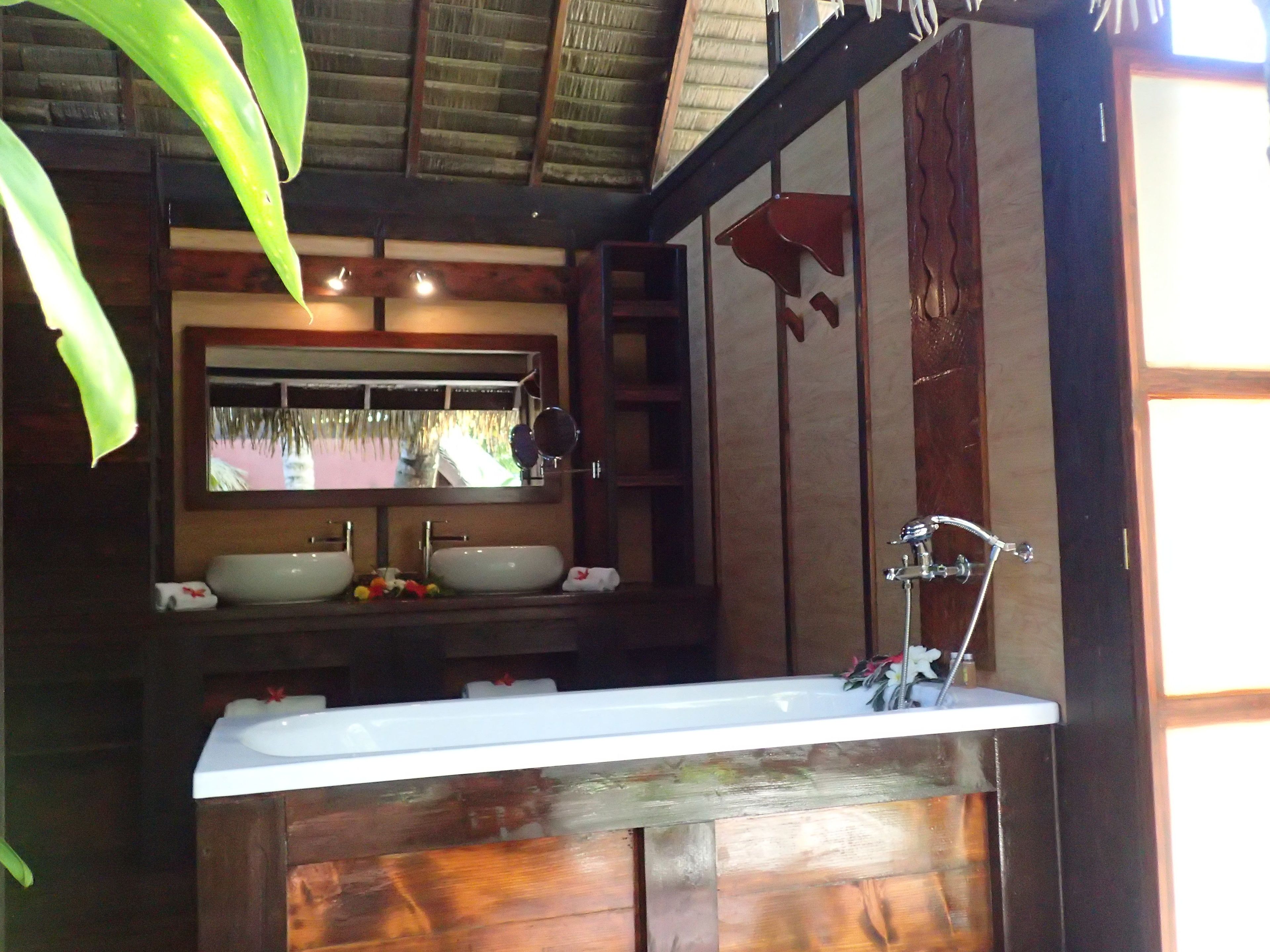 A bathroom with a wooden vanity, a large mirror, and a sink.