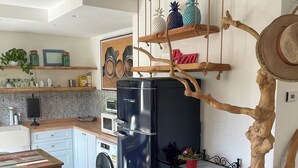 Een moderne keuken met een zwarte koelkast, houten planken, een wasmachine en een eethoek met een tafel en stoelen.