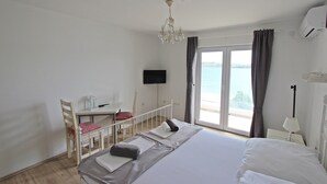 A hotel room with a bed, a desk, a chair, a TV, and a view of the sea. - Villa Danica - Apartment (studio) 2 persons - direct at sea - 4 star (Betina)