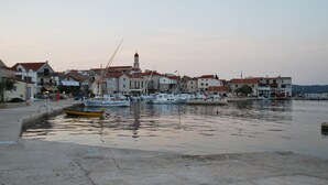 A harbor with boats docked, buildings with red roofs, and a prominent tower. - Villa Danica - Apartment (studio) 2 persons - direct at sea - 4 star (Betina)