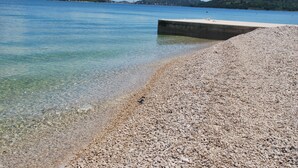 A pebbled beach with clear water and distant hills. - Villa Danica - Apartment (studio) 2 persons - direct at sea - 4 star (Betina)