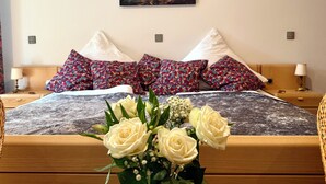 Ein ordentlich eingerichtetes Schlafzimmer mit Bett, Kissen, einem Nachttisch, einer Lampe und einem Wandbild.