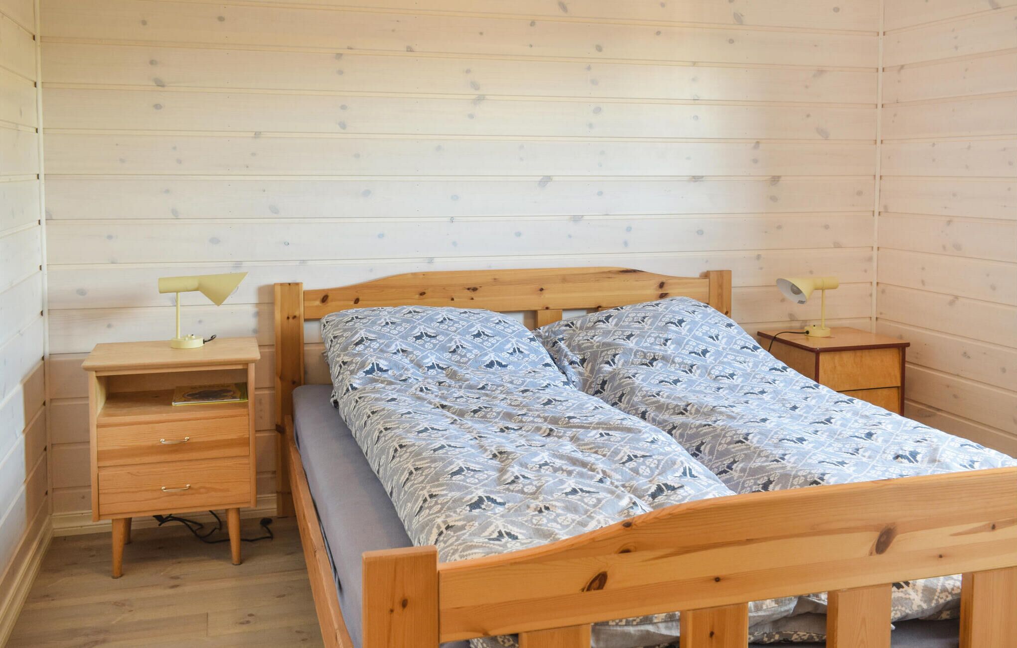 A small, cozy bedroom with a wooden bed, two bedside tables, and a nightstand.