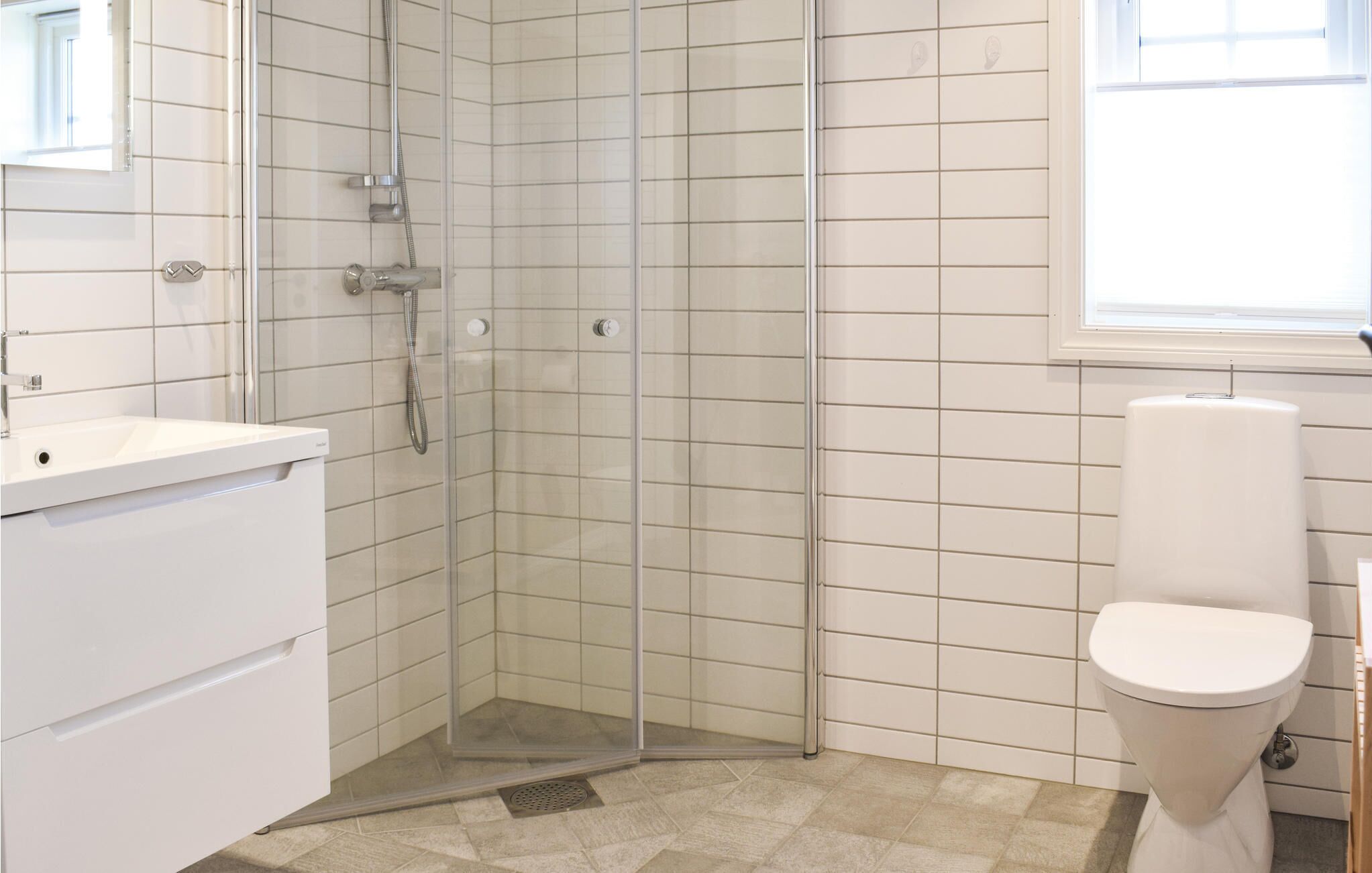 A modern bathroom with a glass shower enclosure, a white sink, and a toilet.