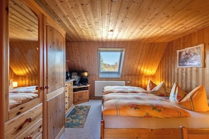 A wooden cabin bedroom with a bed, dresser, and a window.