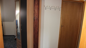 A hallway with a wooden wardrobe, a coat rack, and a closed door. - Apartment 1 "Auerhahn" up to 4 persons + cot - dog allowed (Wernigerode)
