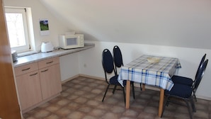 A small kitchen with a microwave, toaster, and a table with chairs. - Apartment 1 "Auerhahn" up to 4 persons + cot - dog allowed (Wernigerode)