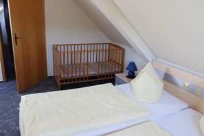 Une chambre avec un berceau, un lit avec un oreiller et une table de chevet avec une lampe.