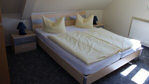 A single bed with a wooden frame, two bedside tables with lamps, and a radiator on the wall. - Apartment 1 "Auerhahn" up to 4 persons + cot - dog allowed (Wernigerode)