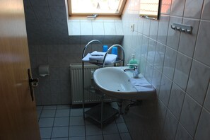Une petite salle de bain avec un puits de lumière, un lavabo blanc, un porte-serviettes et un radiateur.
