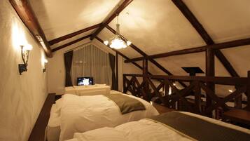 Een gezellig slaapkamer op zolder met twee bedden, houten balken, een televisie en een raam met gordijnen.