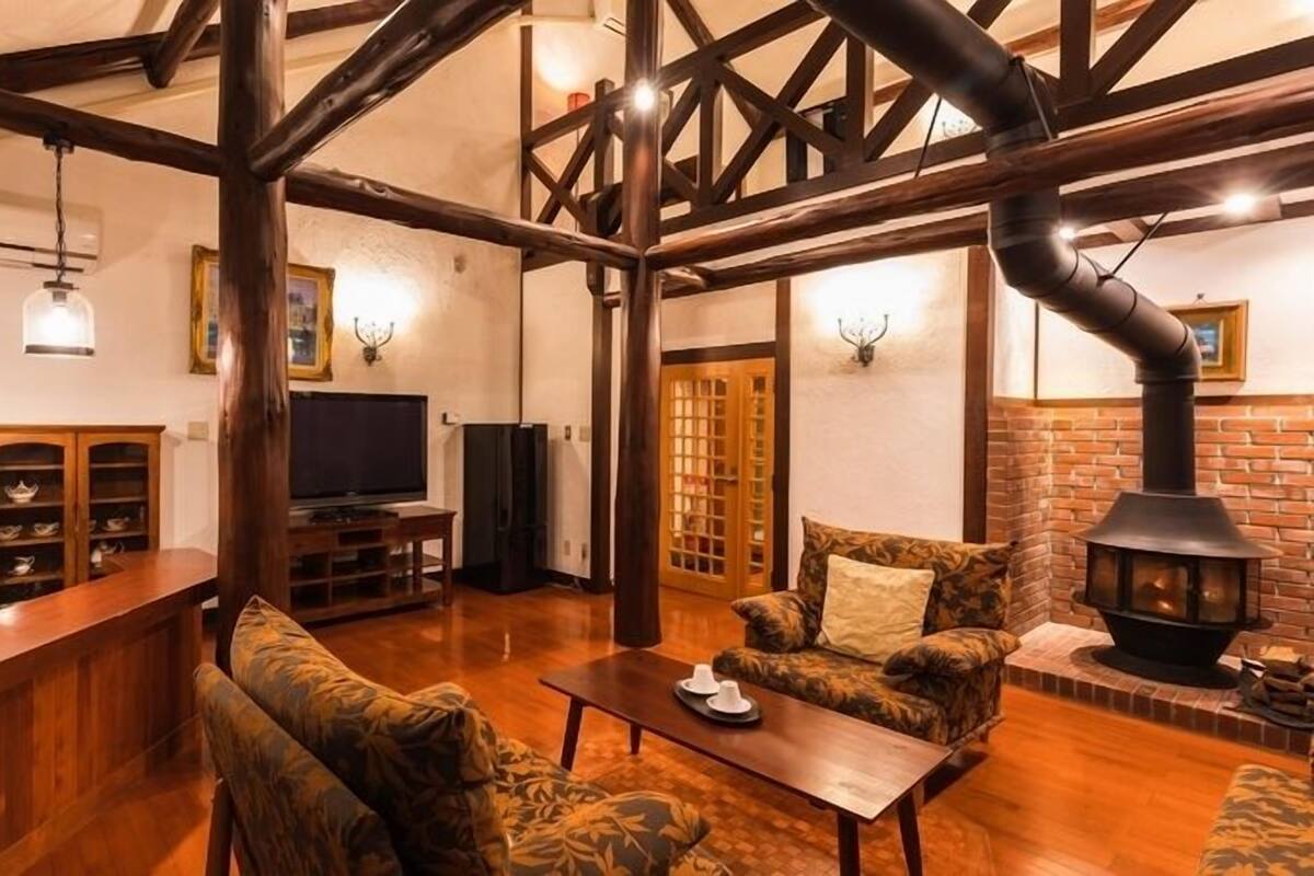 Ein gemütliches Wohnzimmer mit Kamin, Holzbalken, Fernseher und Barbereich.