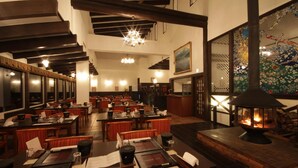 A restaurant with wooden tables and chairs, a fireplace, and traditional decor. - Hotel Jogakura (Aomori)