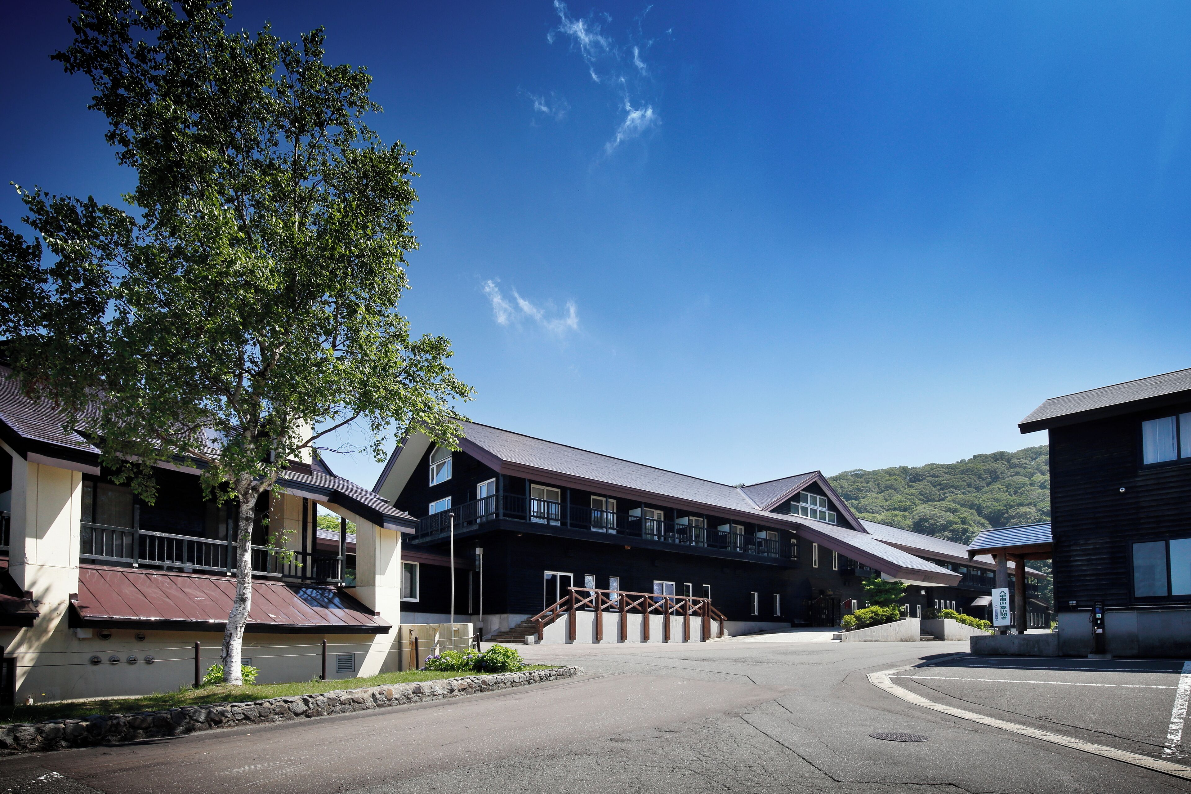 Un hotel con diseño arquitectónico moderno, que cuenta con una escalera destacada que conduce a la entrada, un área exterior cubierta y vistas del paisaje circundante.