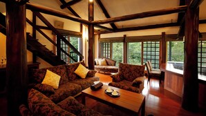 A spacious living area with a high ceiling, wooden beams, and large windows offering a view of the outdoors. - Hotel Jogakura (Aomori)