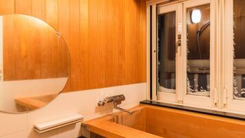 A wooden-paneled bathroom with a large mirror, a sink, and a window with frosted glass.