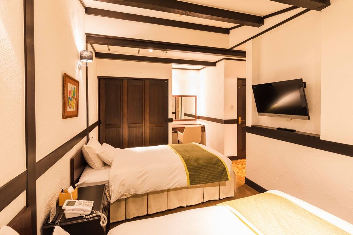 Ein Hotelzimmer mit Bett, Nachttisch, Lampe, Fernseher und einer Tür zum Badezimmer.