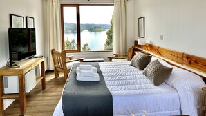 Une chambre avec un grand lit, un bureau avec un ordinateur, une chaise et une vue sur un lac.