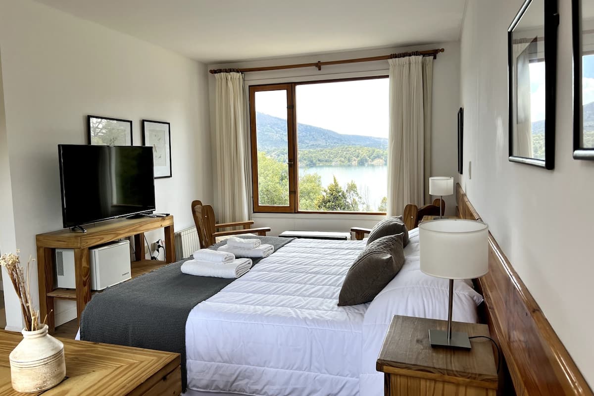 Ein Hotelzimmer mit Bett, Fernseher, Schreibtisch und Seeblick.