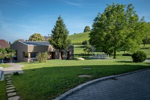 A modern building with a metal roof, surrounded by a well-maintained lawn and trees.