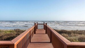 Una passerella di legno che conduce all'oceano, con le onde che si infrangono sullo sfondo.
