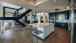 Cucina spaziosa con un'isola grande, mobili scuri e una moderna ventola a soffitto.