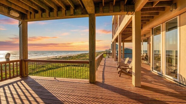 Un terrazza in legno con vista sull'oceano e sulla spiaggia, dotata di ringhiere in legno e arredi da esterno.
