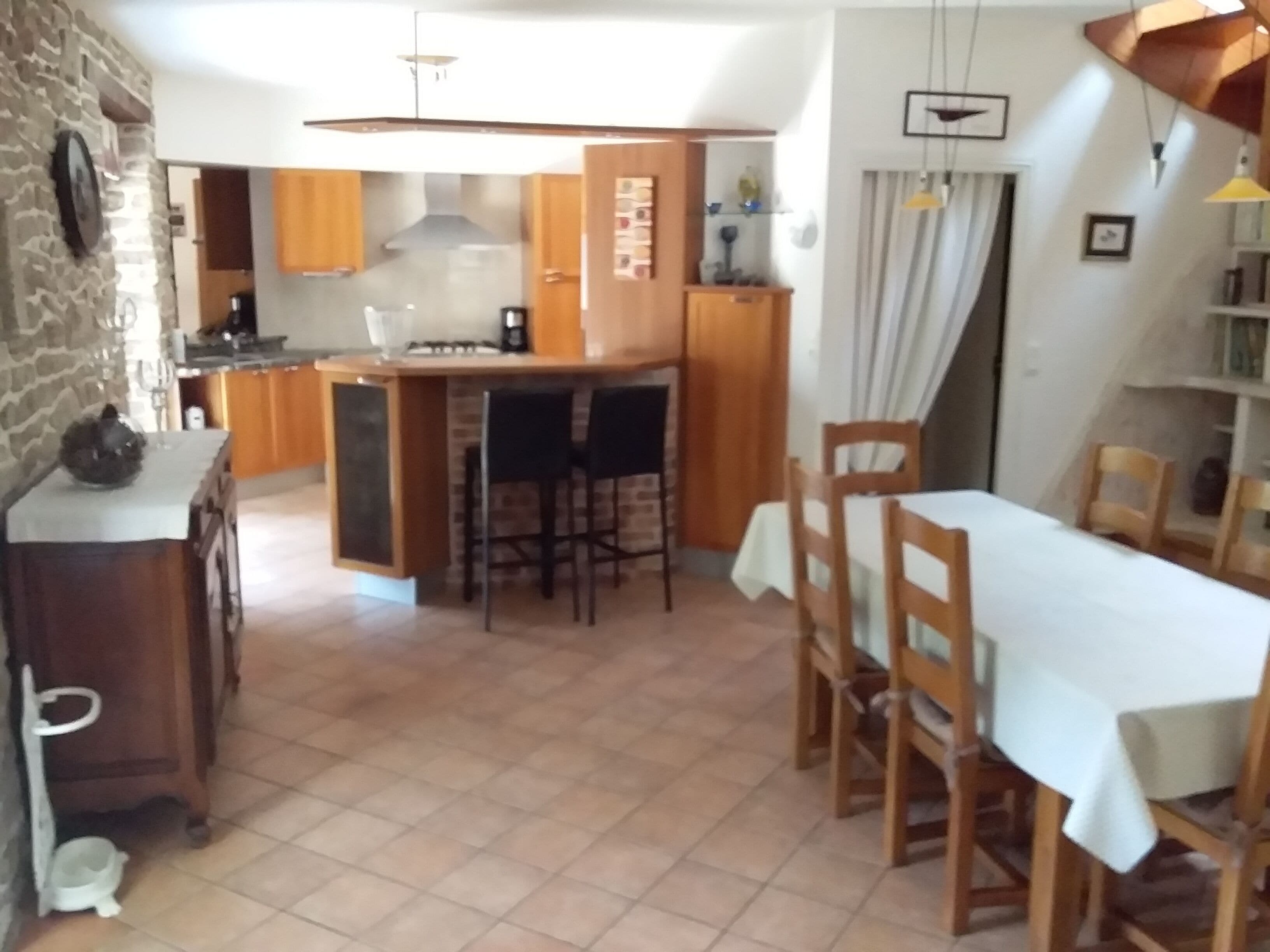 Una cocina con una isla central, armarios de madera y una zona de comedor con mesa y sillas.