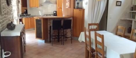 Una cocina con una isla central, armarios de madera y una zona de comedor con mesa y sillas.