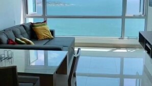 A modern living room with a large window offering a view of the sea. - Apartamentos  Cartagena 01 (Cartagena)
