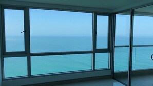A room with large floor-to-ceiling windows offering a view of the ocean. - Apartamentos  Cartagena 01 (Cartagena)