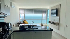 A modern kitchen with a large island, a built-in oven, and a view of the sea through large windows. - Apartamentos  Cartagena 01 (Cartagena)